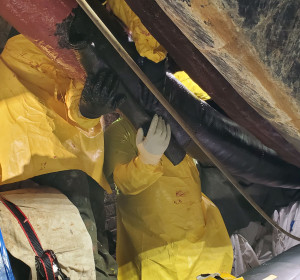 Applicators wrapping black composite pipe fabric around a corroded pipe.