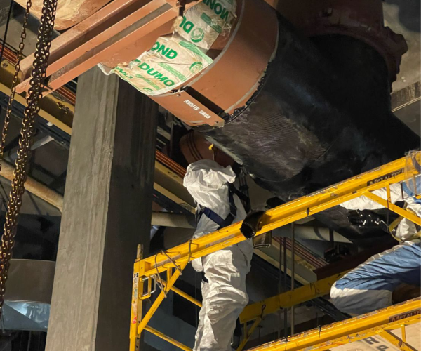 View looking up at workers repairing section of large pipeline.