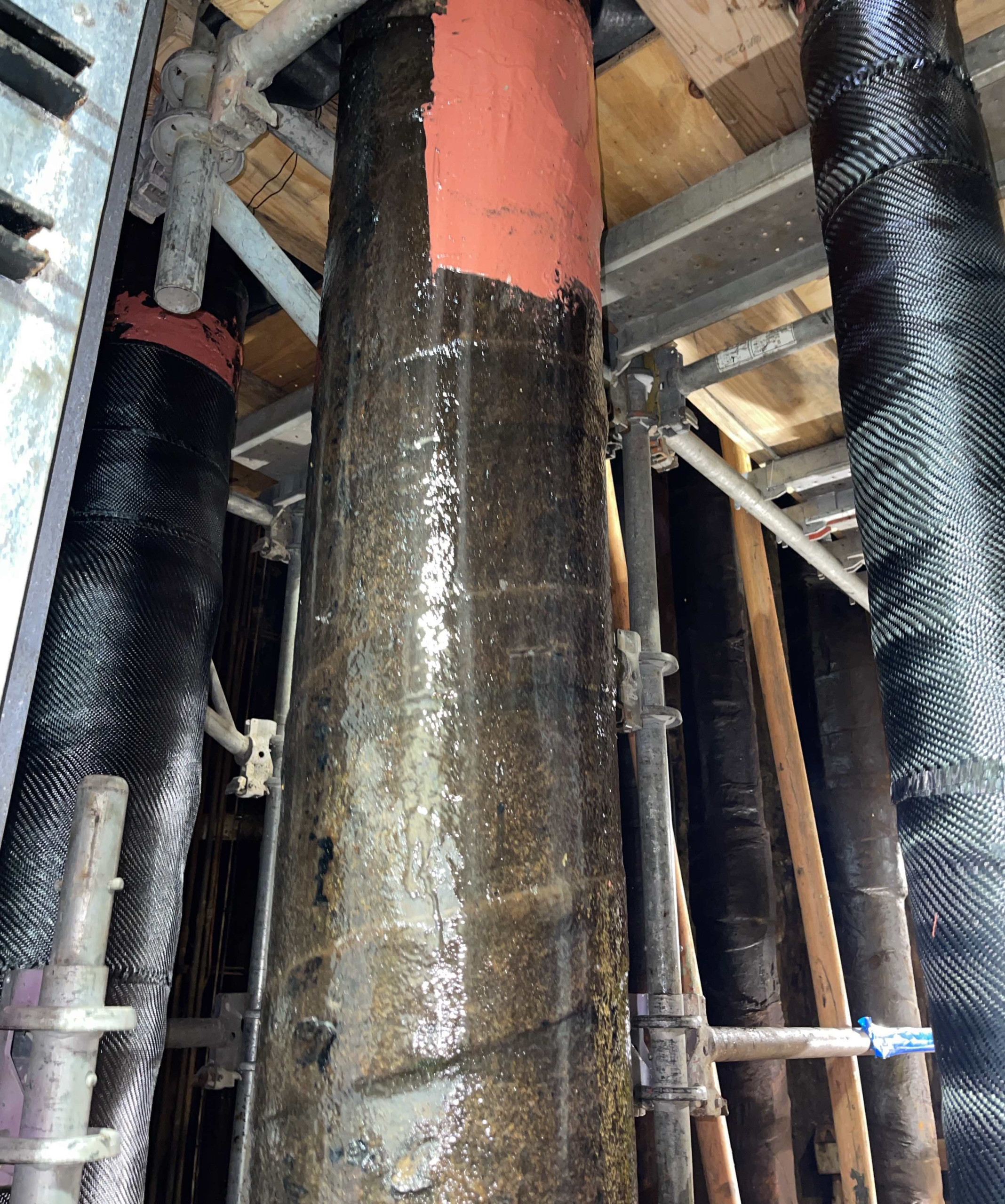 Three vertical pipes with composite pipe repair wrapped around them.