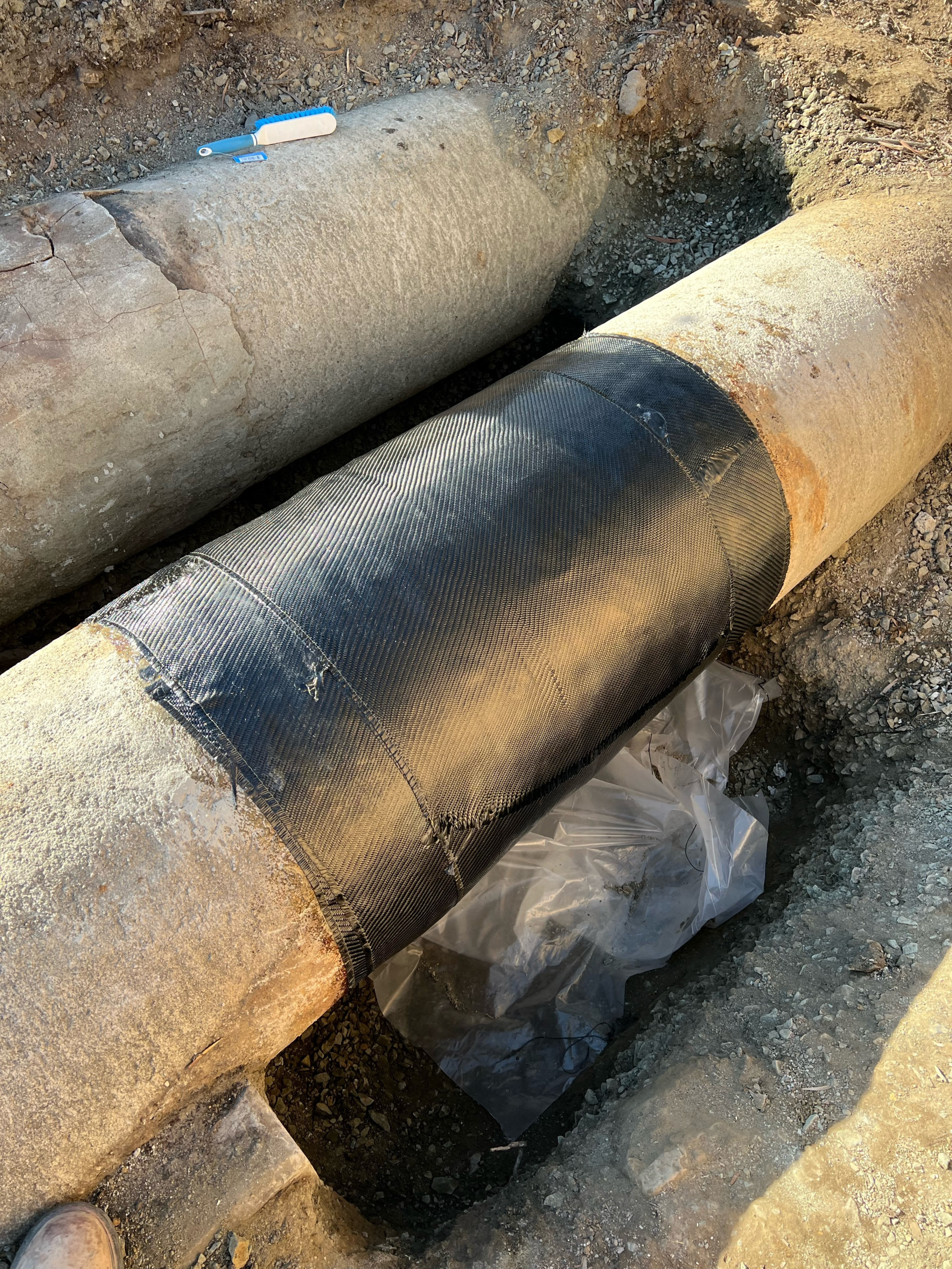 Composite pipe repair for waterwater treatment plant. Image of pipe wrapped in black composite wrap.