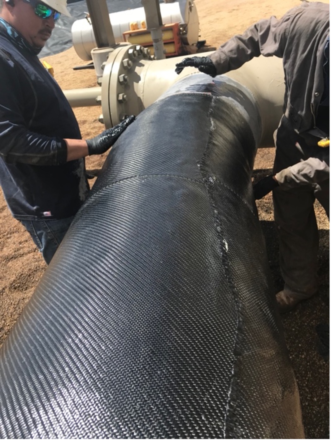 Maintenance team applying composite repair to pipeline.