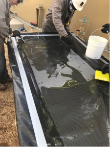 Workers saturating the carbon fiber composite material.