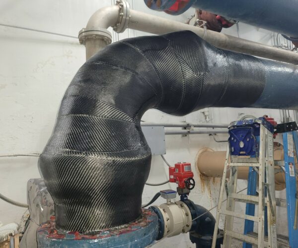 Large pipe elbow inside a water and wastewater facility wrapped in carbon fiber composite.