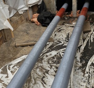 View of gray and red coated composite repair wrapped on a pipe in a trench