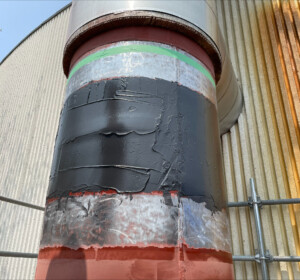 Large diameter vertical pipe outside facility wrapped around the width with carbon fiber composite repair material.
