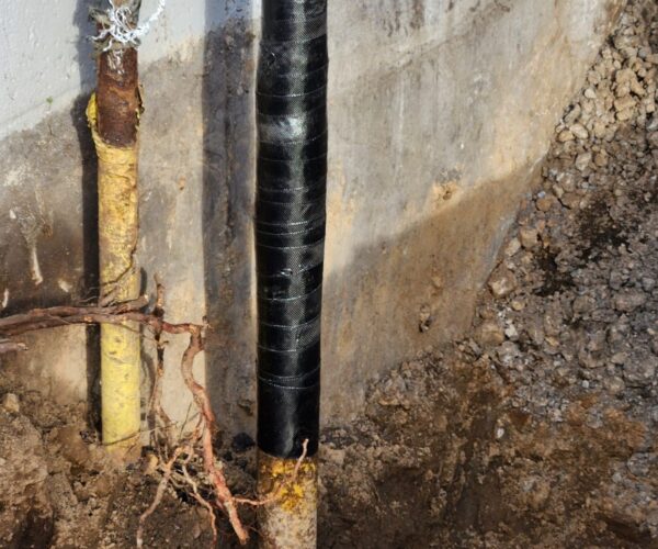 Smaller diameter vertical pipe with a black composite fiber repair wrapped around the outside