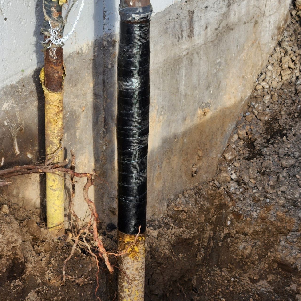 Smaller diameter vertical pipe with a black composite fiber repair wrapped around the outside