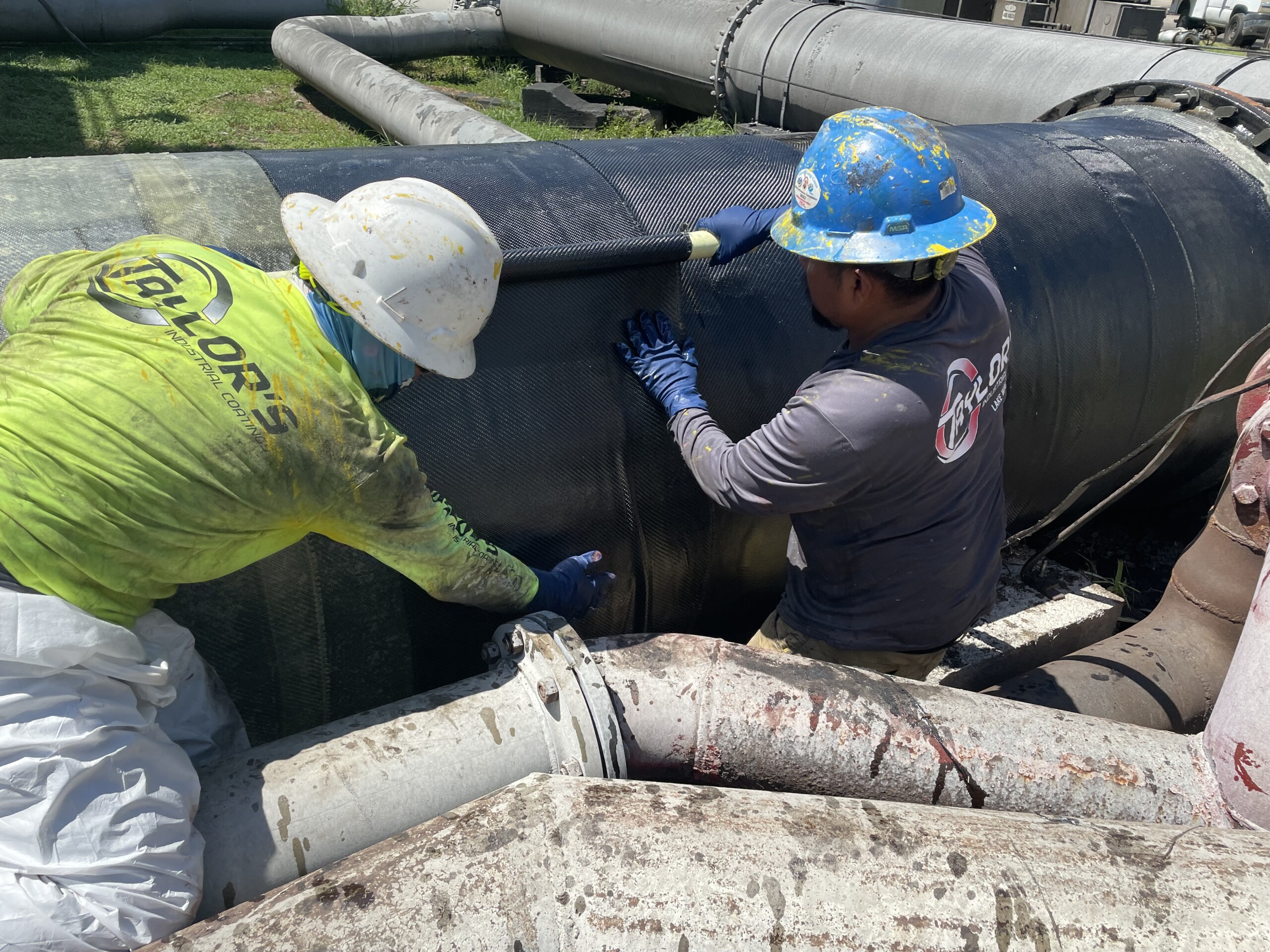 Composite wrap repair for pipelines being applied by two workers.