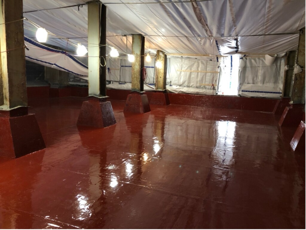 Concrete structure coated in a red top coat after a infrastructure repair was completed with composites